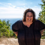 Smiling woman in a sheer top on a mountain in western North Carolina.