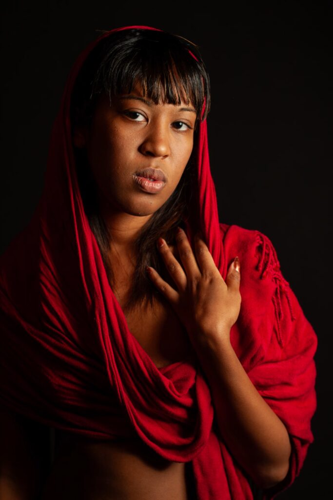 Color portrait of an African American woman draped in red at a Durham boudoir photography studio.