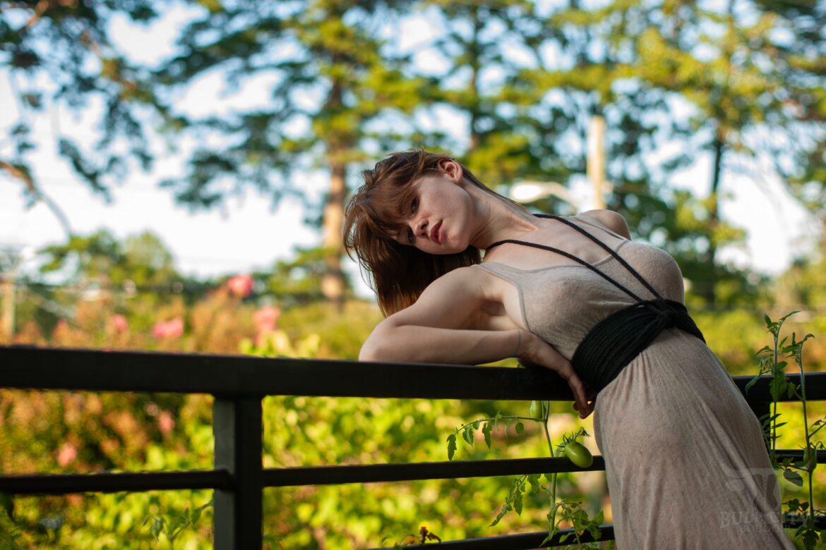 Boudoir photography session image of a redheaded woman in a sheer dress on a balcony